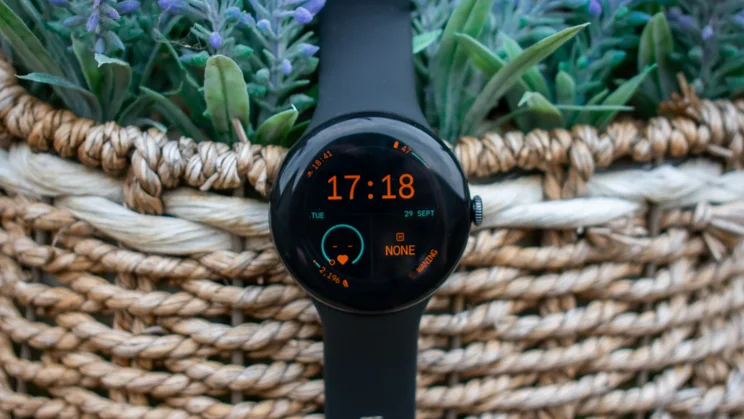 Google Pixel Watch 5 in a hanging basket, displaying the home screen