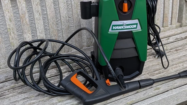 Hawksmoor High Pressure Washer 108 bar on a slatted bench with its hose coiled, the trigger gun and lance in front and the plug and power cable at right.