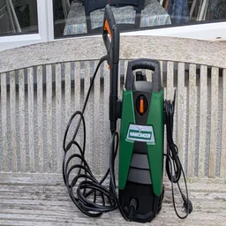 Hawksmoor High Pressure Washer 108 bar upright on a garden bench with the trigger gun stowed on its side holder and the power cable wrapped on the other.