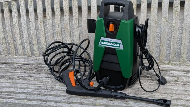 Hawksmoor High Pressure Washer 108 bar on a slatted bench with its hose coiled, the trigger gun and lance in front and the plug and power cable at right.