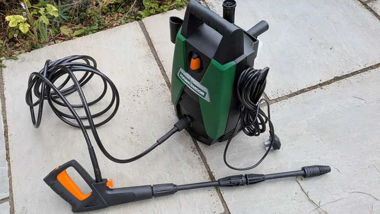 Hawksmoor High Pressure Washer 108 bar seen from above on paving, with the hose coiled beside it, the spray gun and lance in front and the power cable wrapped on the side.