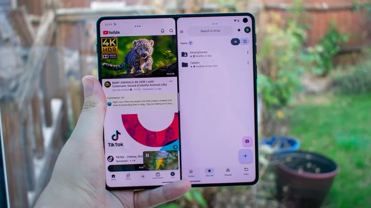 Motorola Razr Fold unfolded in hand, split-screen apps on the display