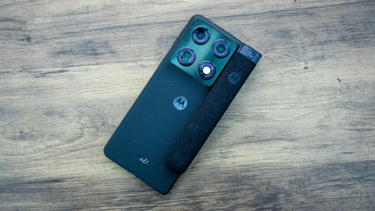 Motorola Razr Fold lying face down on a table with the Moto Pen Ultra charging case sitting on it