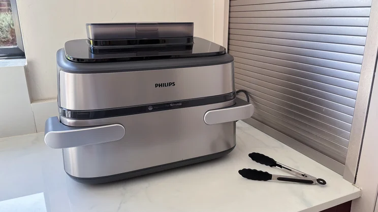 The Philips Airfryer 5000 Series Megabasket with Steam on a kitchen counter, alongside its tongs