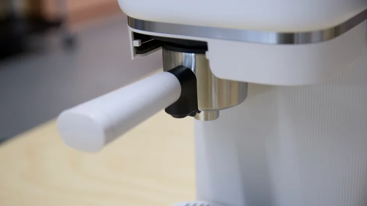 A close up of the Philips Baristina's brew group with portafilter in place after brewing