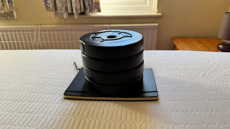 A stack of weights and a notebook being used to test sinkage on the REM-Fit Pocket 1000 Hybrid mattress