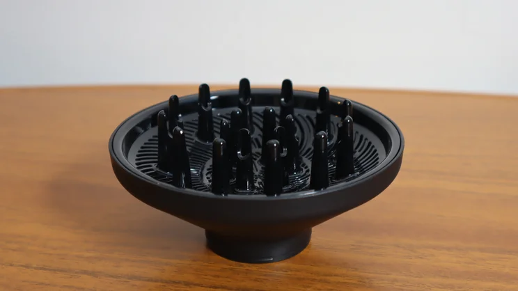 A closeup of the Revlon One Step Power Move hair dryer's diffuser attachment, on a wooden table