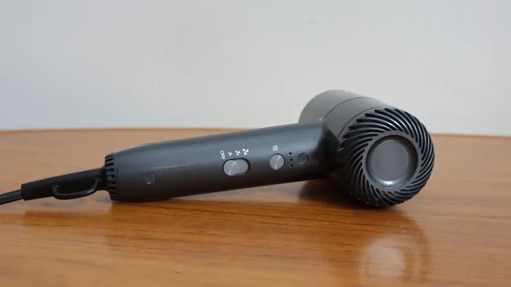 The Revlon One Step Power Move hair dryer, lying on its side on a wooden table