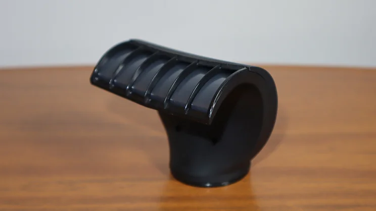 A closeup of the Revlon One Step Power Move hair dryer's Smooth & Shine Finisher attachment, on a wooden table