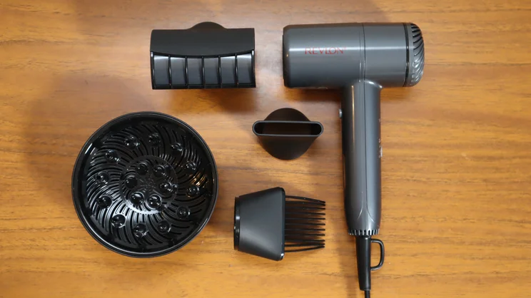 A bird's eye view of the Revlon One Step Power Move hair dryer and its attachments, on a wooden table