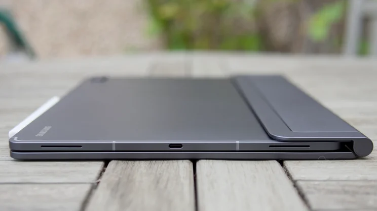 Side view of the Samsung Galaxy Tab S12 Ultra folded flat against its cover, showing the USB-C port, two speaker grilles and the hinge cylinder
