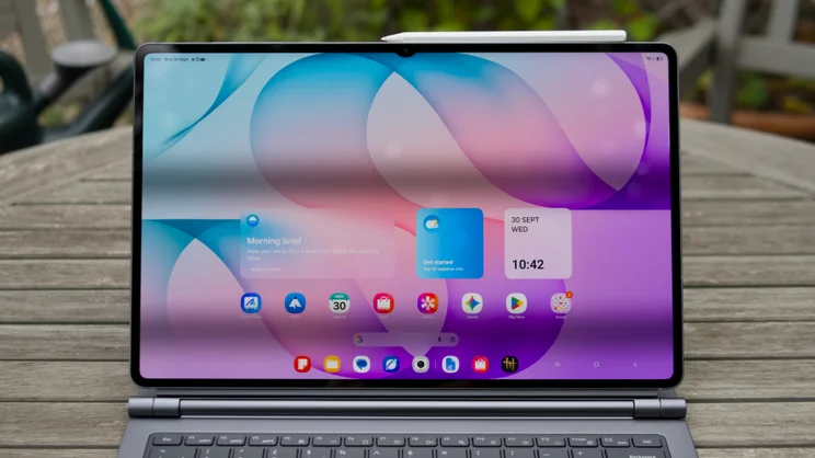 Samsung Galaxy Tab S12 Ultra attached to its keyboard cover, seen head-on with a white stylus on the top edge and a colourful home screen