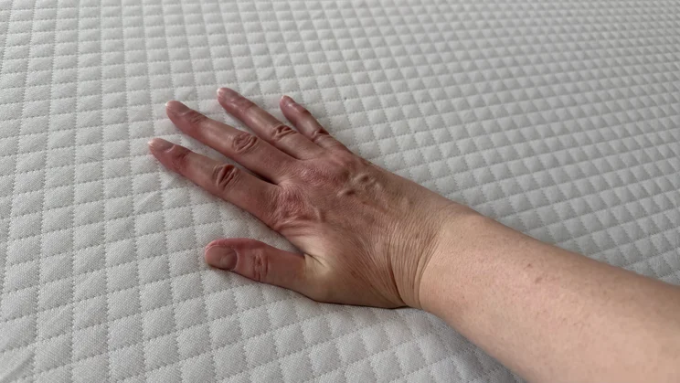 A hand pressing down on the Simba Simbatex Cool mattress