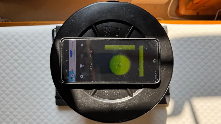 A bird's eye view of a stack of weights and a smartphone, being used to test tilt at the edge of the Simba Simbatex Cool mattress