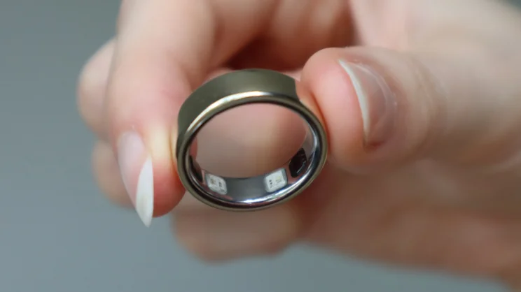 The Oura ring 5 being held between thumb and forefinger