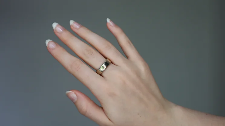 The Oura ring 5 being worn on someone's middle finger 03