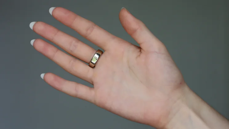The Oura ring 5 being worn on someone's middle finger _0