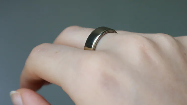 The Oura ring 5 being worn on someone's middle finger _01