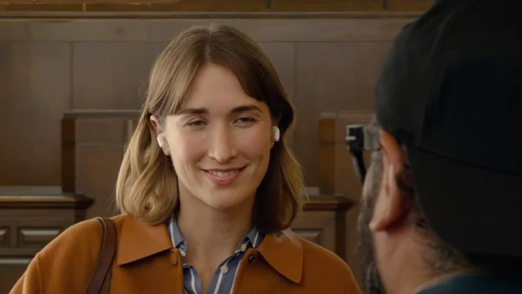 A woman wearing the Apple AirPods 5 wireless earbuds using the Live Translation feature