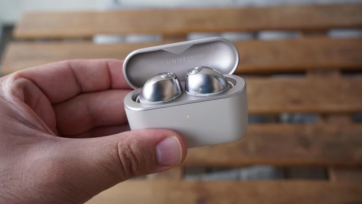 The Sennheiser Momentum True Wireless 5 in their charging case being held with their lid open