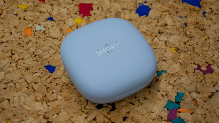 The Shokz OpenFit Air 2's charging case with the lid closed on a cork table