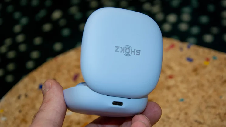 The Shokz OpenFit Air 2's charging case being held in a hand to show the USB-C port