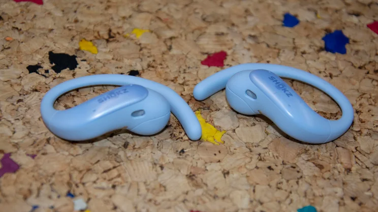 The earbuds of the Shokz OpenFit Air 2 side by side, both laying flat on a cork table