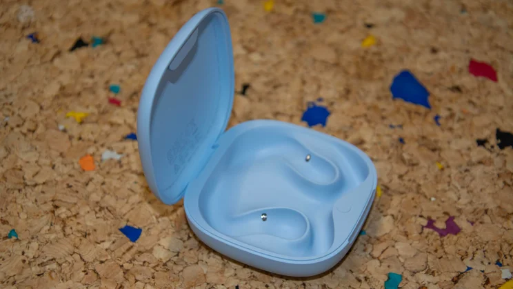The empty charging case of the Shokz OpenFit Air 2 with its lid open on a cork table