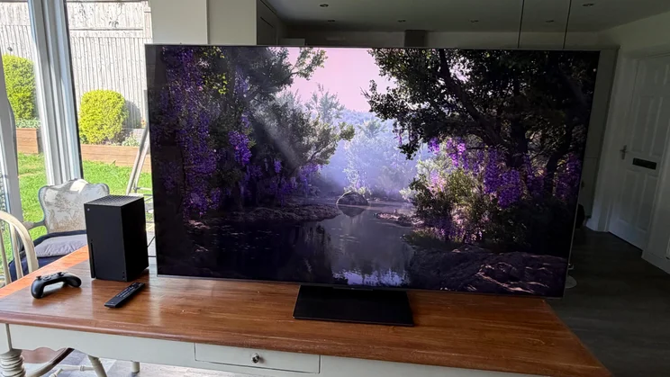 Front view of the TCL C8L SQD Mini LED TV next to the Xbox Series X