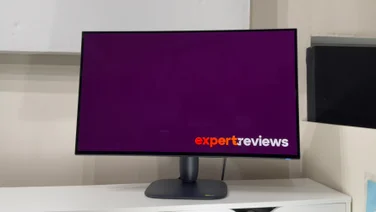 Alienware AW3226Q gaming monitor viewed from the front on a white shelf, its screen showing a purple Expert Reviews logo screen.