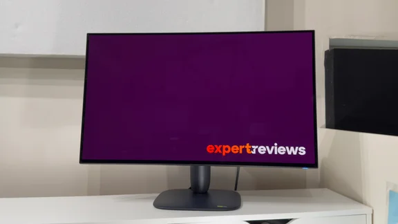 Alienware AW3226Q gaming monitor viewed from the front on a white shelf, its screen showing a purple Expert Reviews logo screen.
