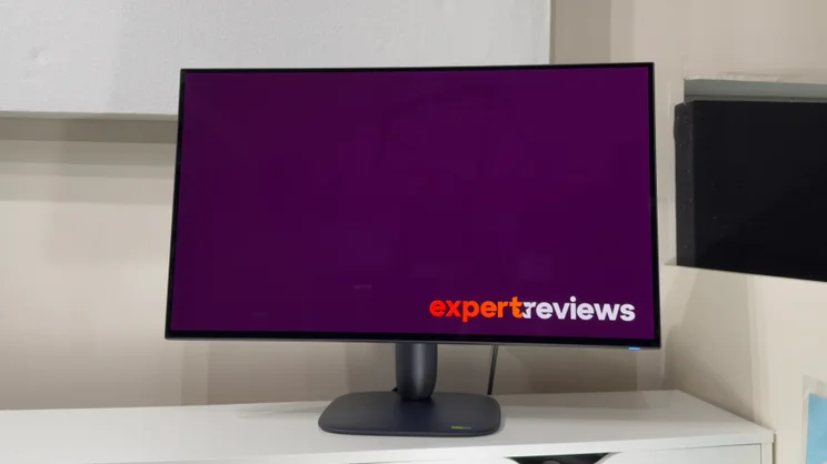 Alienware AW3226Q gaming monitor viewed from the front on a white shelf, its screen showing a purple Expert Reviews logo screen.
