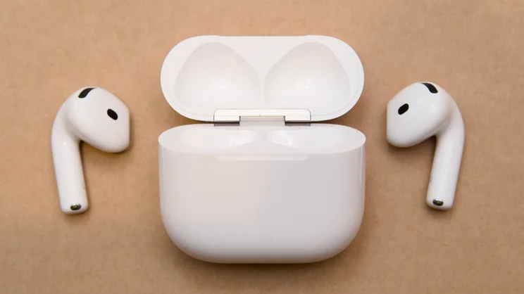 Apple AirPods 5 open charging case in the centre with the left and right earbuds lying on either side of it