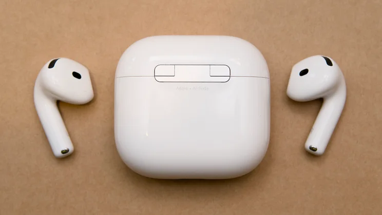 Back of the closed Apple AirPods 5 charging case showing the hinge and Apple AirPods text, with both earbuds lying on either side