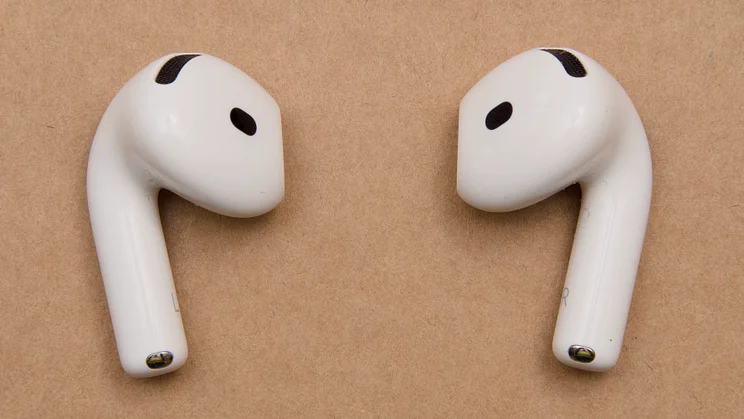 Closer view of the pair of Apple AirPods 5 earbuds, with the mesh vents, black sensor openings and L and R stem markings visible