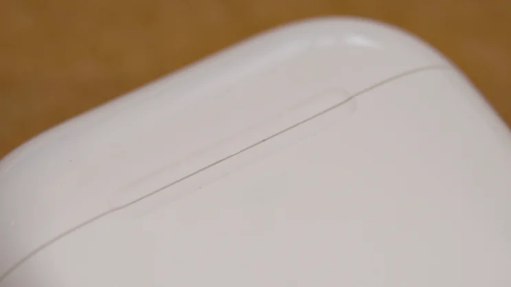 Close-up of the lid seam and thumb-notch indent on the front of the Apple AirPods 5 charging case