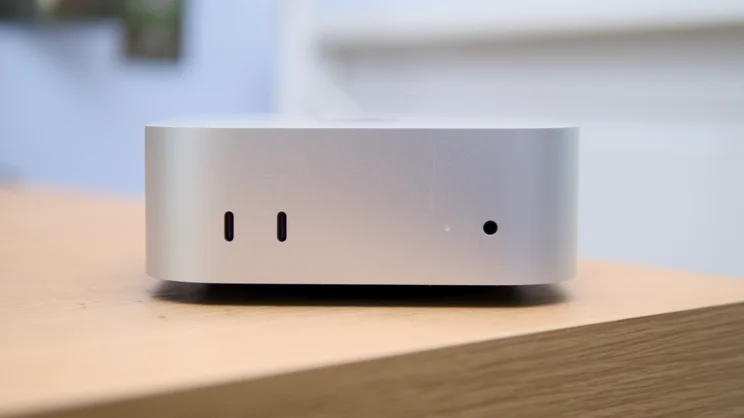 Close-up of the Apple Mac mini (M5 Pro, 2026) front edge, showing two USB-C ports, a status light and a headphone jack.