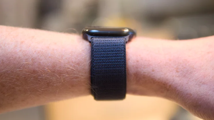 Side view of an Apple Watch Series 12 on a wrist, with a dark woven Sport Loop band wrapped around it.