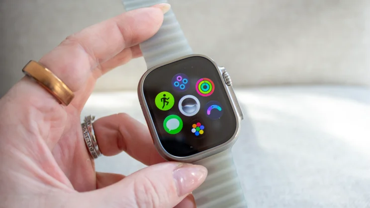 Hand holding the Apple Watch Ultra 4 showing a cluster of icons, including Activity rings, Workout, Messages and the new Readiness app