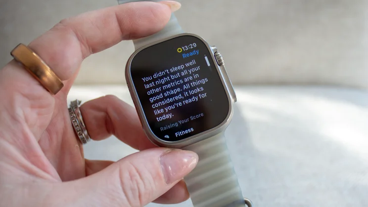 Hand holding the Apple Watch Ultra 4 showing a screen with a message saying sleep was poor but other metrics are in good shape