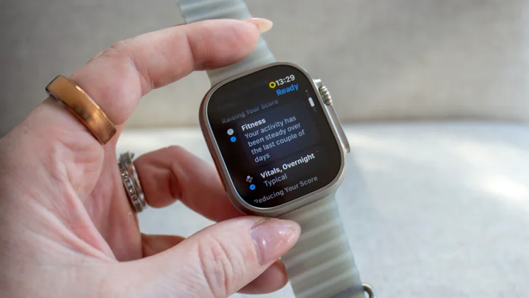 Hand holding the Apple Watch Ultra 4 showing a Ready screen with Fitness and Vitals details