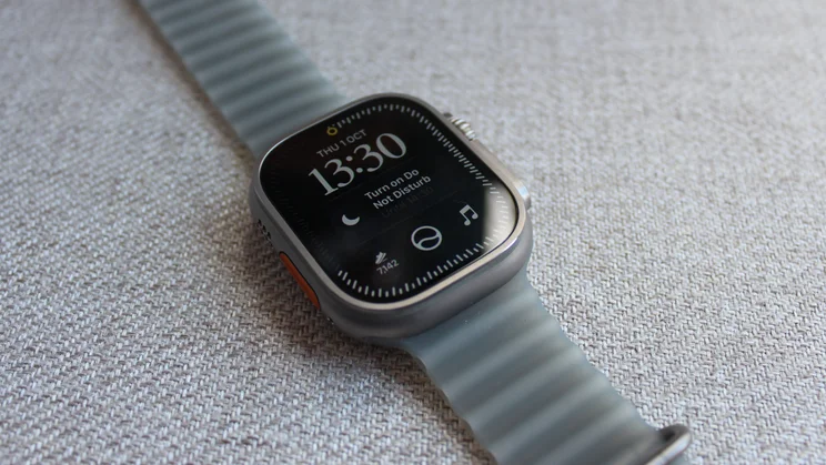 Apple Watch Ultra 4 on woven fabric showing the time 13:30 with a Do Not Disturb prompt, a moon icon and a music button on the new Siri watch face