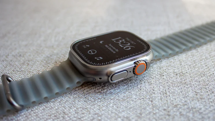Apple Watch Ultra 4 on its side showing the orange-ringed Digital Crown, side button and a Do Not Disturb prompt on the screen