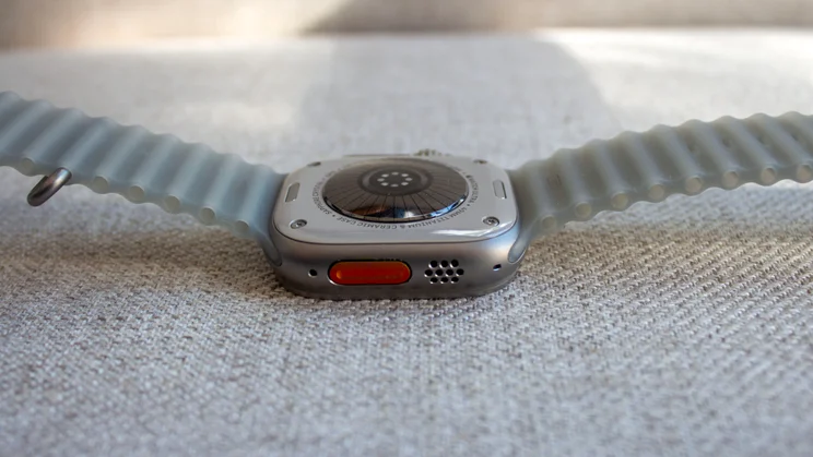 Apple Watch Ultra 4 on its back showing the orange Action button, speaker grille, new heart rate sensor