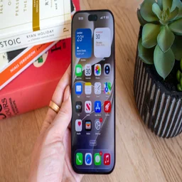 iPhone 18 Pro home screen showing London weather and calendar widgets alongside a grid of app icons, held in han