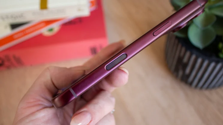 Close-up of a burgundy iPhone 18 Pro's side buttons, phone tilted diagonally in hand