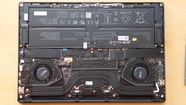 Internal view of the Asus ProArt P16 RTX Spark laptop with the base panel removed, showing the large battery, two cooling fans, copper heat pipes and motherboard.