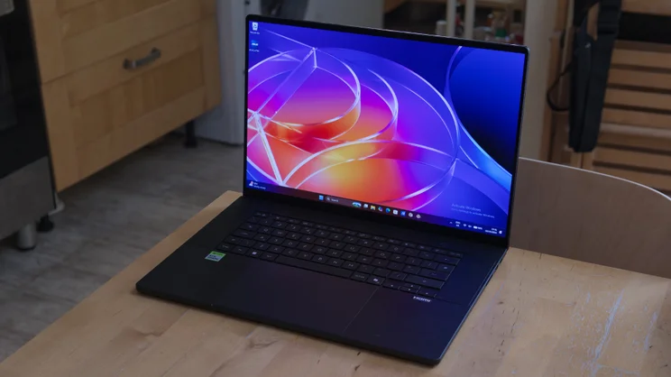 Three-quarter view of the Asus ProArt P16 RTX Spark laptop on a wooden table, showing the open screen, black keyboard, large touchpad and green Nvidia RTX Spark sticker.