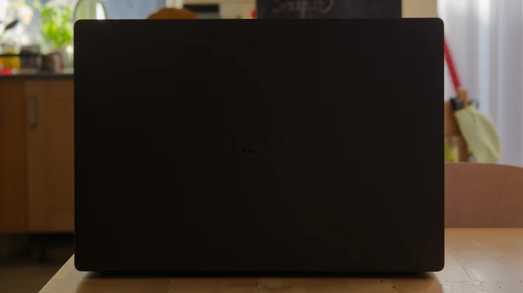 Rear shot of the Asus ProArt P16 RTX Spark laptop, open in a dimly lit kitchen, the dark matte surface with the ProArt logo barely visible at its centre.