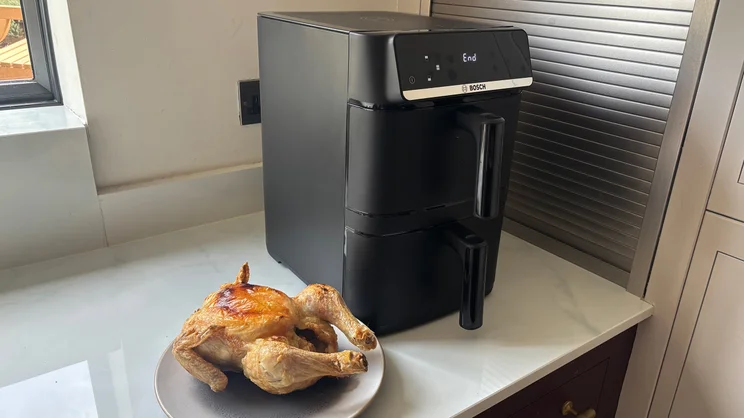 The Bosch Series 6 Double Stack Drawer Air Fryer on a kitchen worktop, next to a plate of cooked chicken